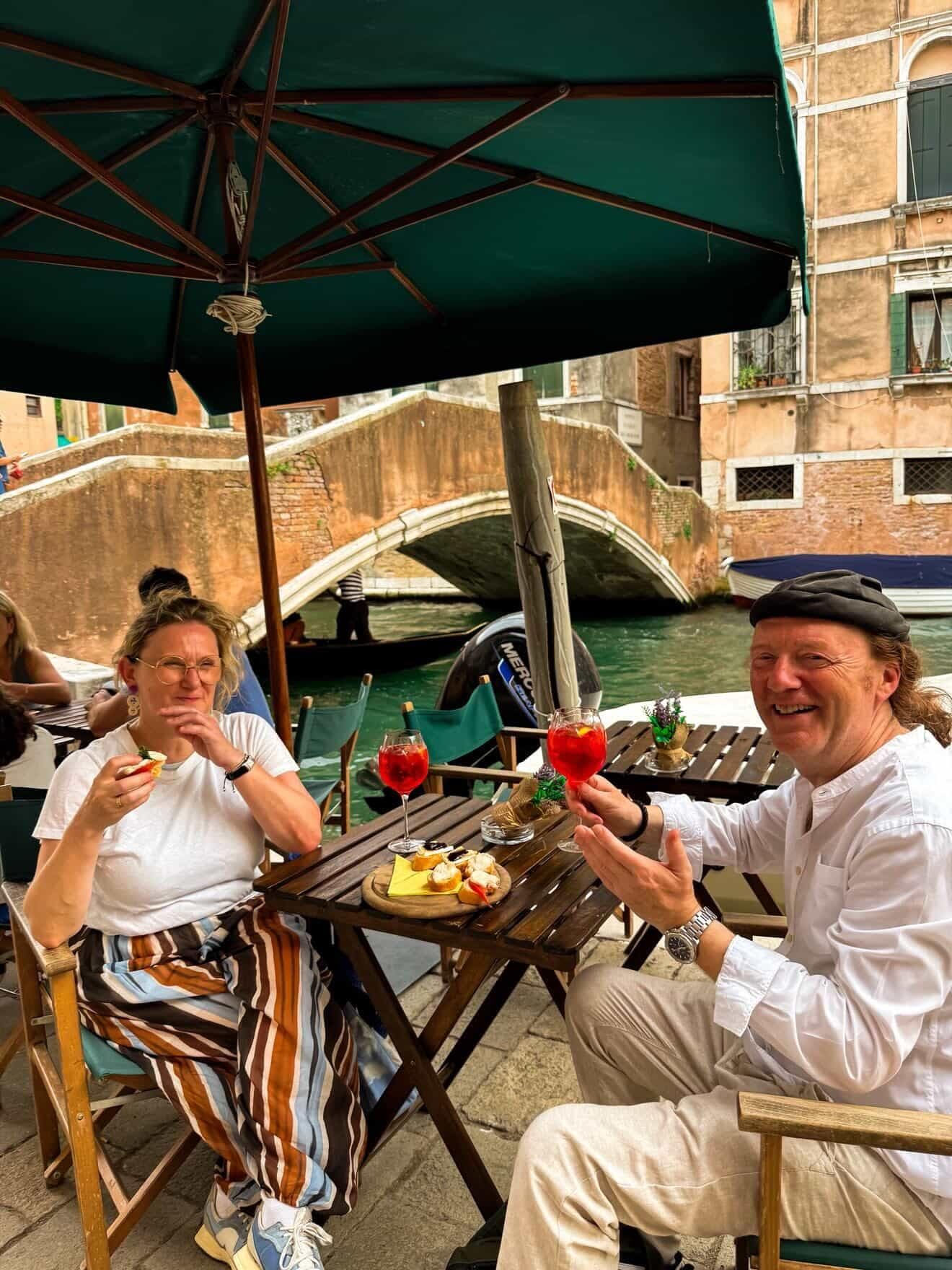 Guests toasting with spritz at a canal-side table