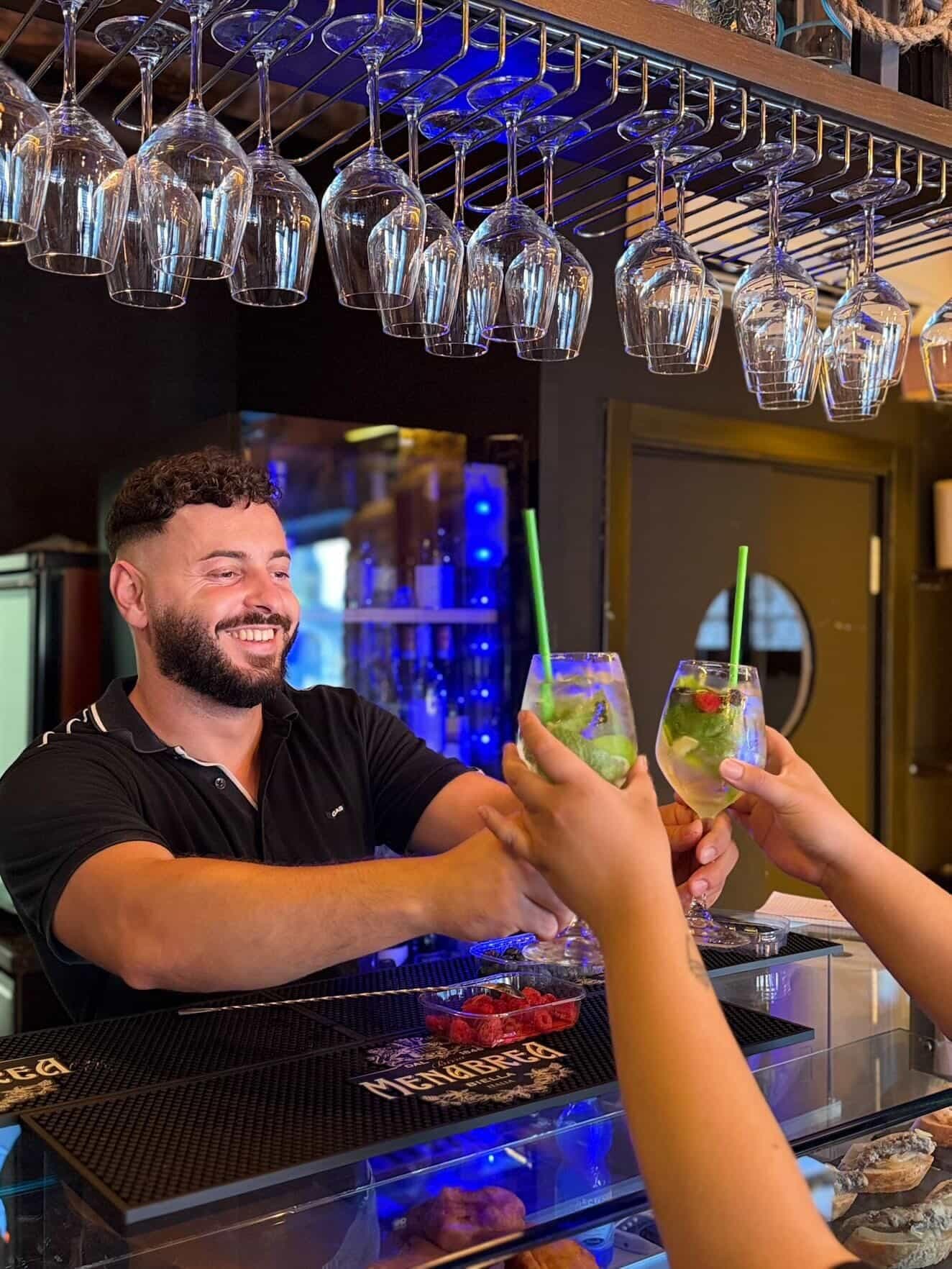 Bartender serving fresh mojitos to smiling guests